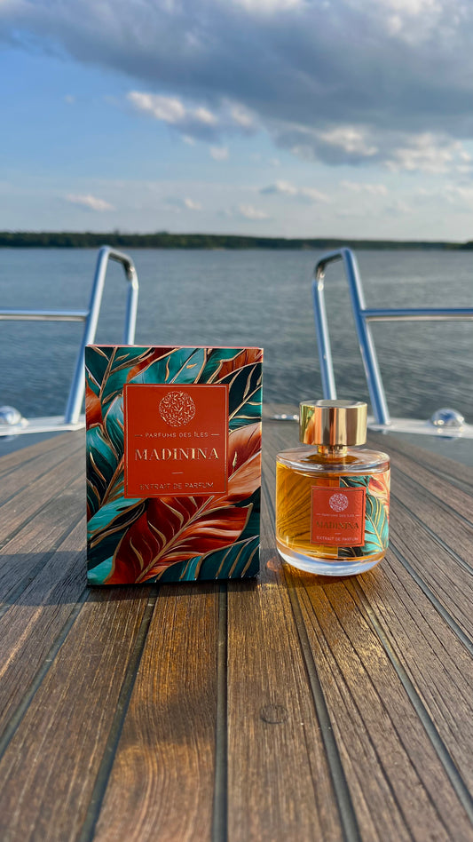 Marinina Parfüm 100ml links die Box, rechts das Parfüm. Produkt steht auf einem Boot im Hintergrund ein See mit Wolken im Himmel