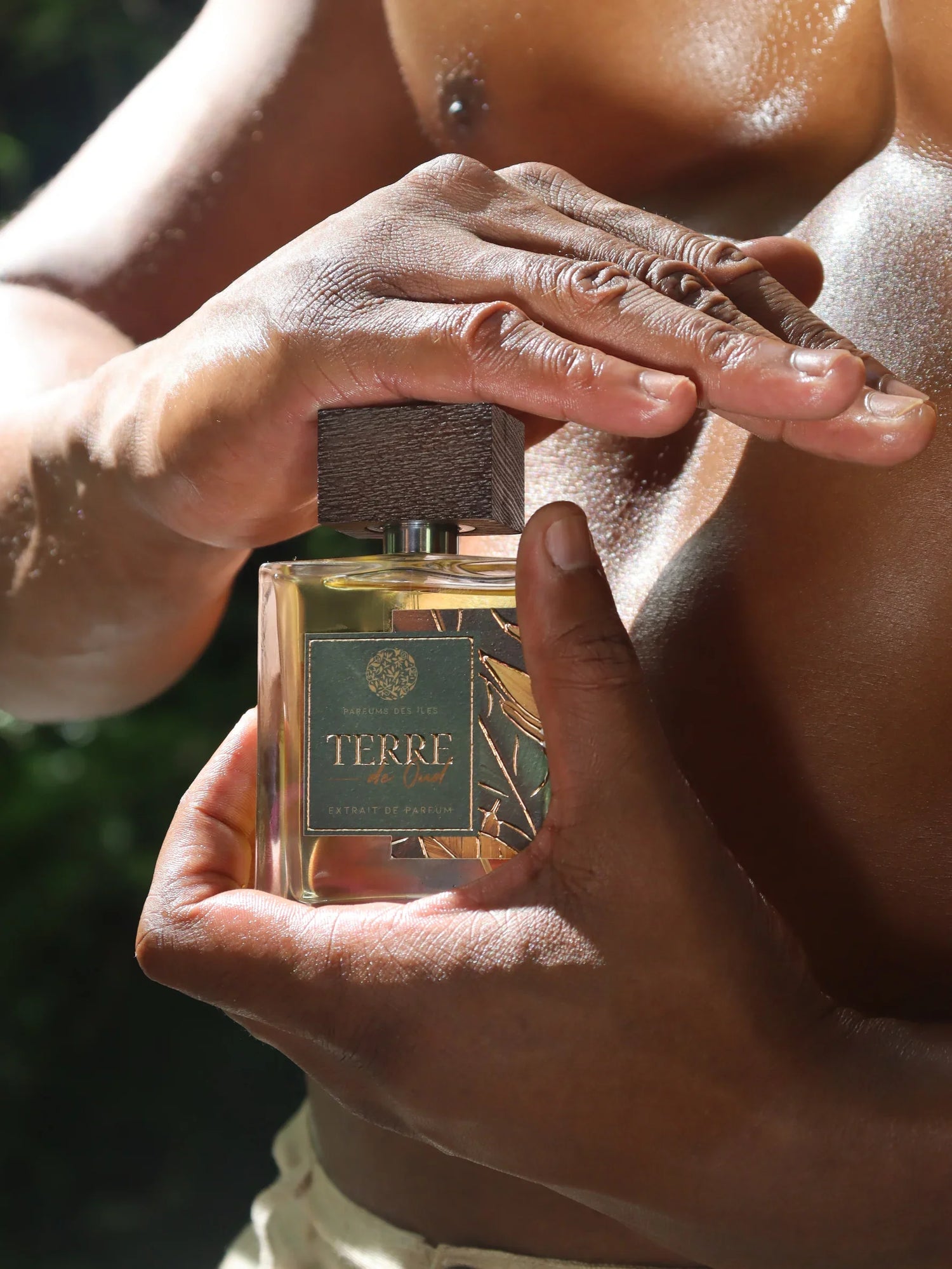 Terre de Oud Parfüm 100ml gehalten in den Händen eines dunkelhäutigen Mannes der oberkörperfrei ist