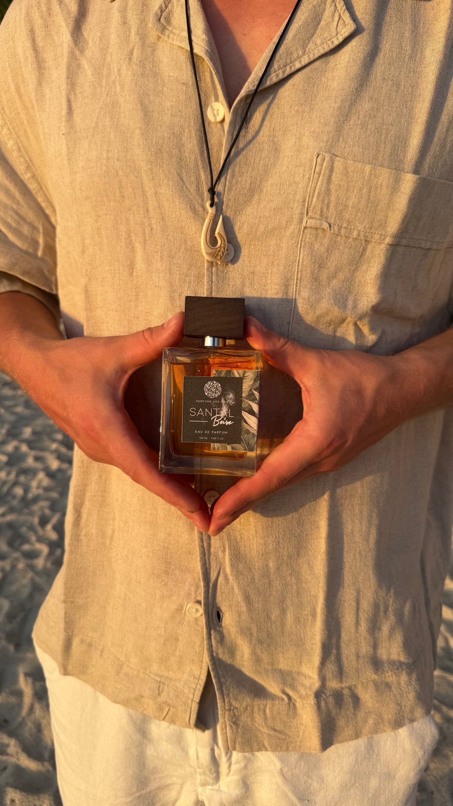 Parfüm Santal in den Händen gehalten von einem Mann. Mann trägt ein Hemd und eine Kette