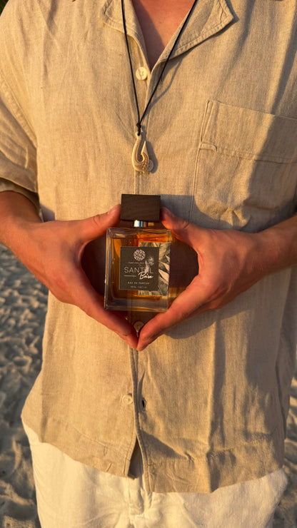 Parfüm Santal in den Händen gehalten von einem Mann. Mann trägt ein Hemd und eine Kette