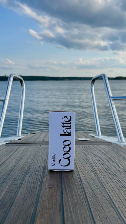 Eau de Toilette Coco latte 100ml. Die Verpackung.  Stehend auf einem Boot im Hintergrund der See mit Wolken.