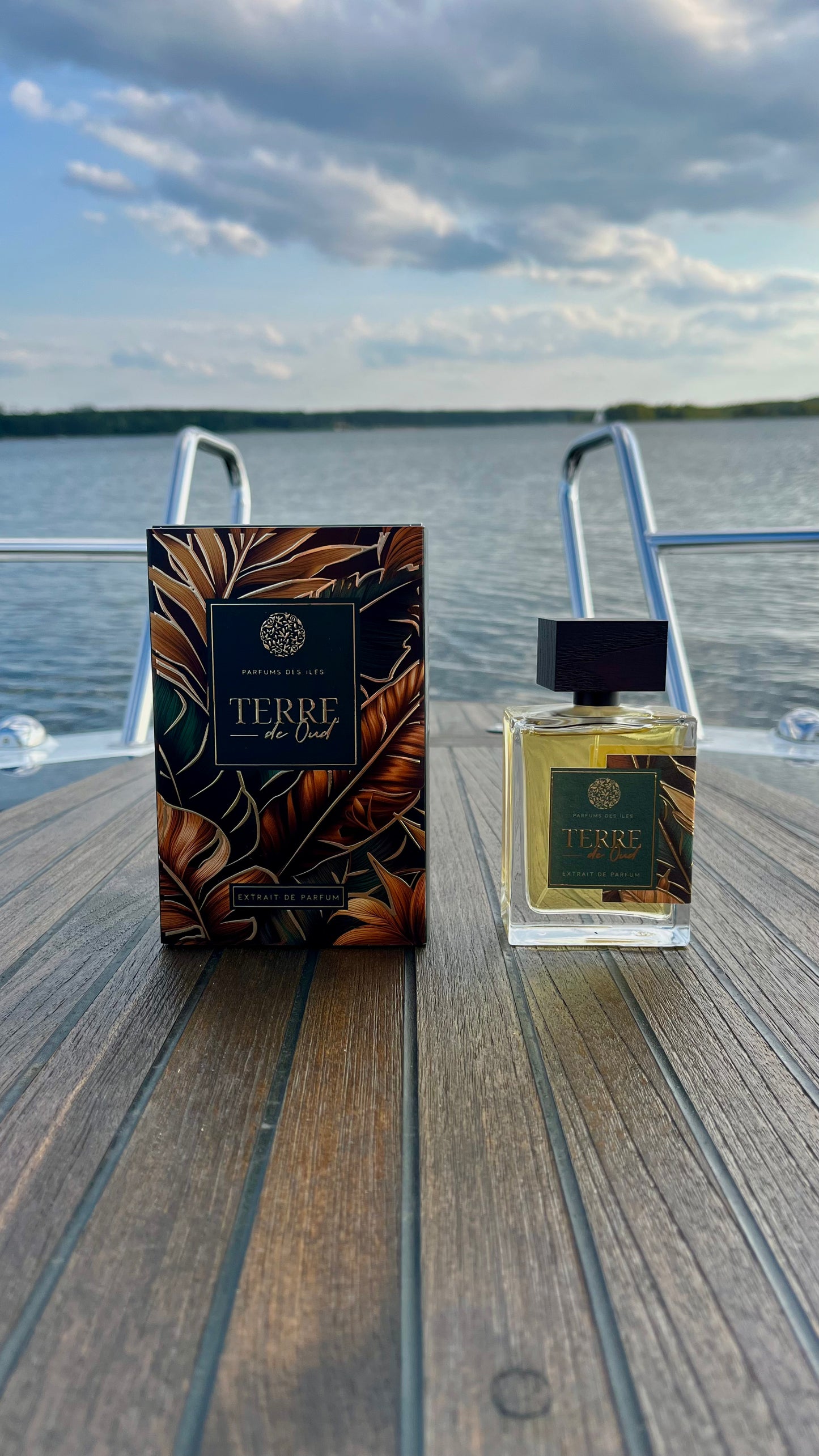 Terre de Oud Parfüm links Karton rechts Flacon 100ml stehend auf einem Boot. Im Hintergrund die Reeling und der See