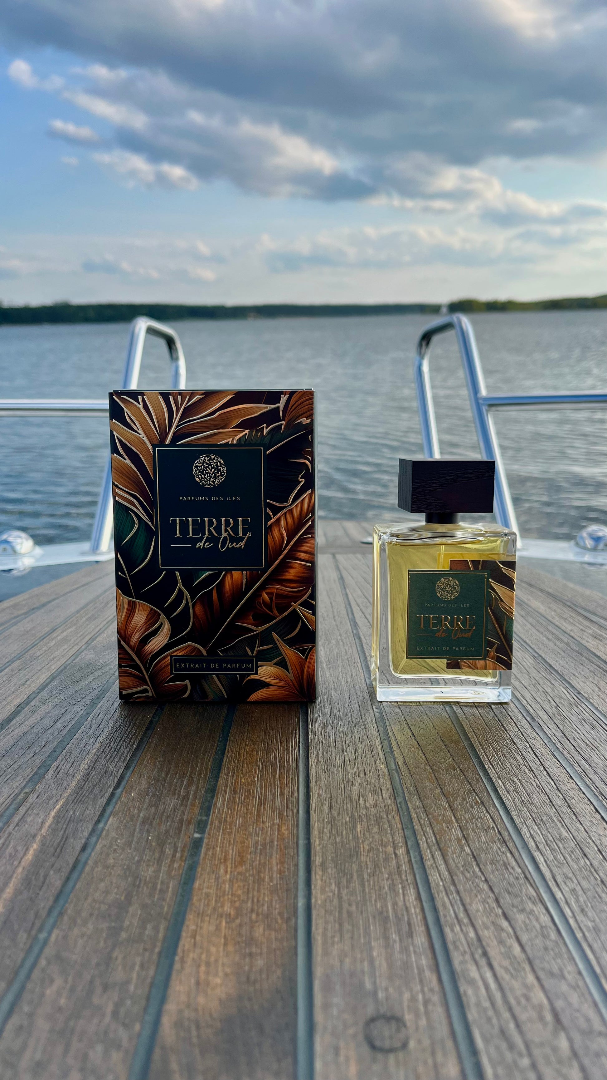 Terre de Oud Parfüm links Karton rechts Flacon 100ml stehend auf einem Boot. Im Hintergrund die Reeling und der See