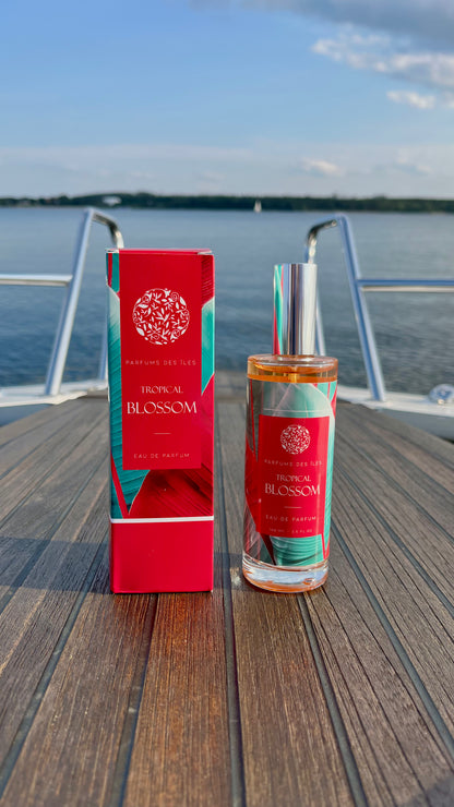 Eau de Parfum Tropical Blossom 100ml links Box, rechts Flacon. Stehend auf einem Boot. Im Hintergrund die Reling und der See