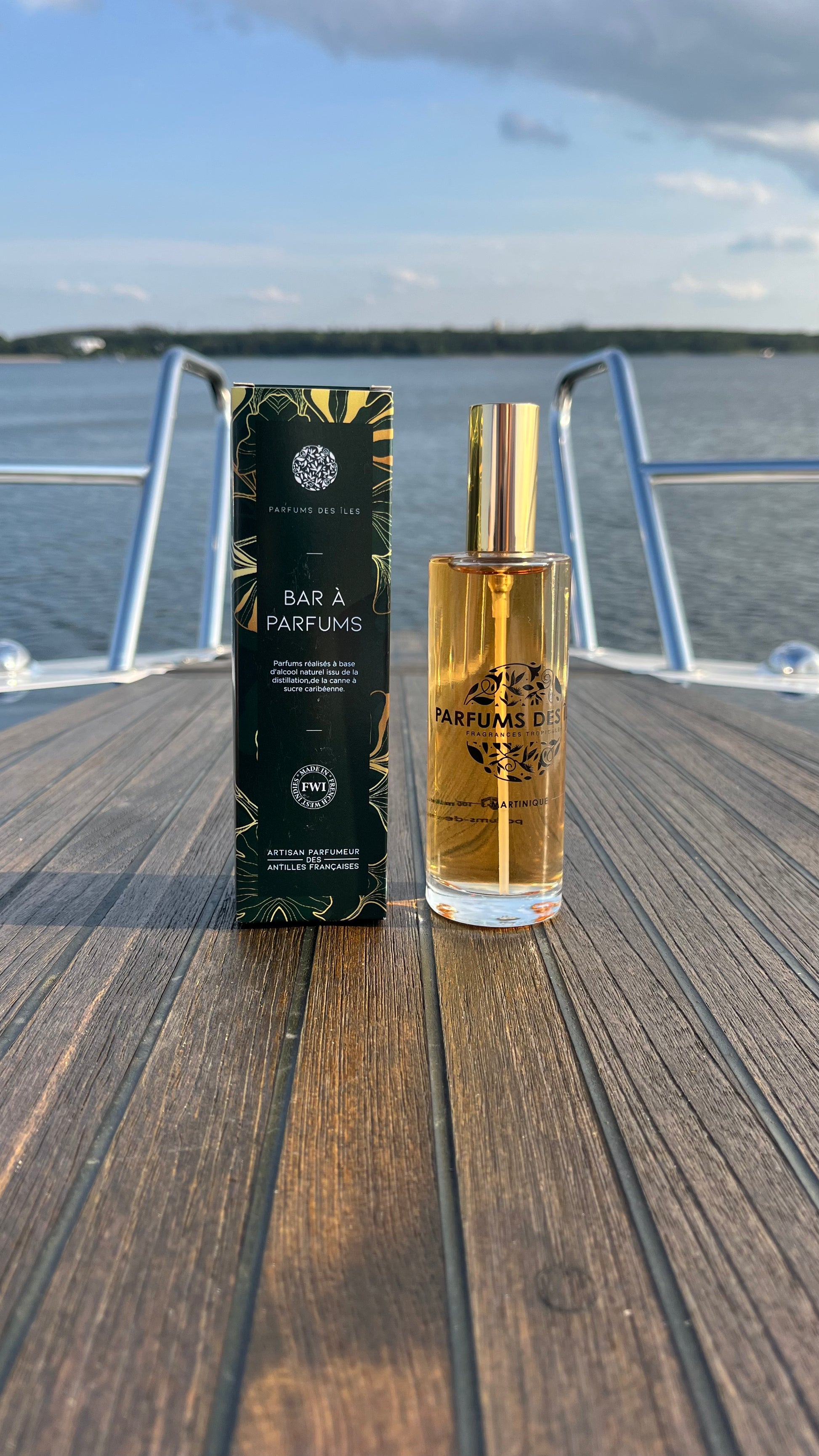 Eau de Parfum Signature Femme 100ml Flacon rechts, links Box. Stehend auf einem Boot. Im Hintergrund die Reeling und der See
