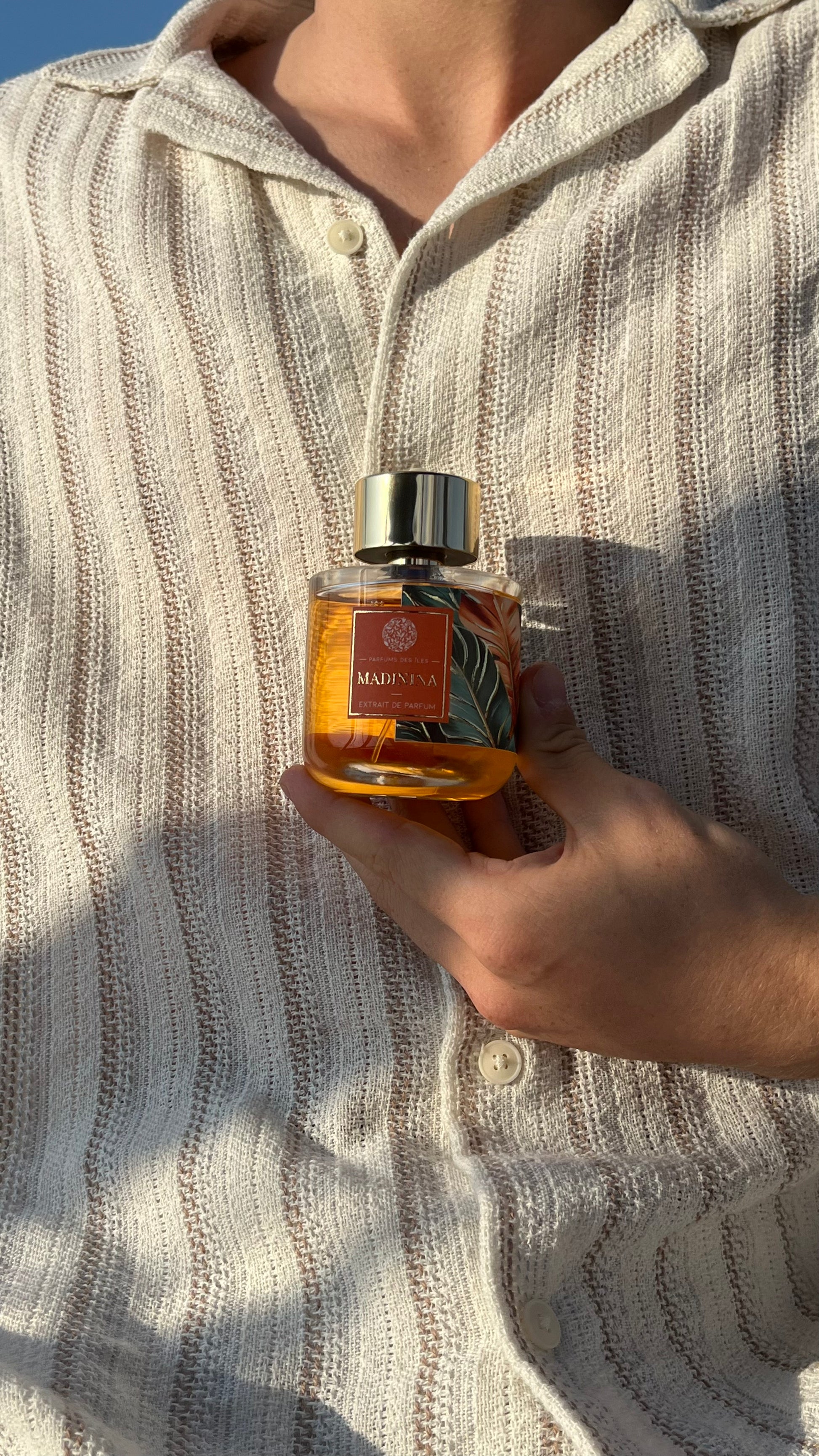 Marinina Parfüm 100ml. Gehalten in der Hand vor dem Körper. Der Körper trägt ein Leinenhemd.