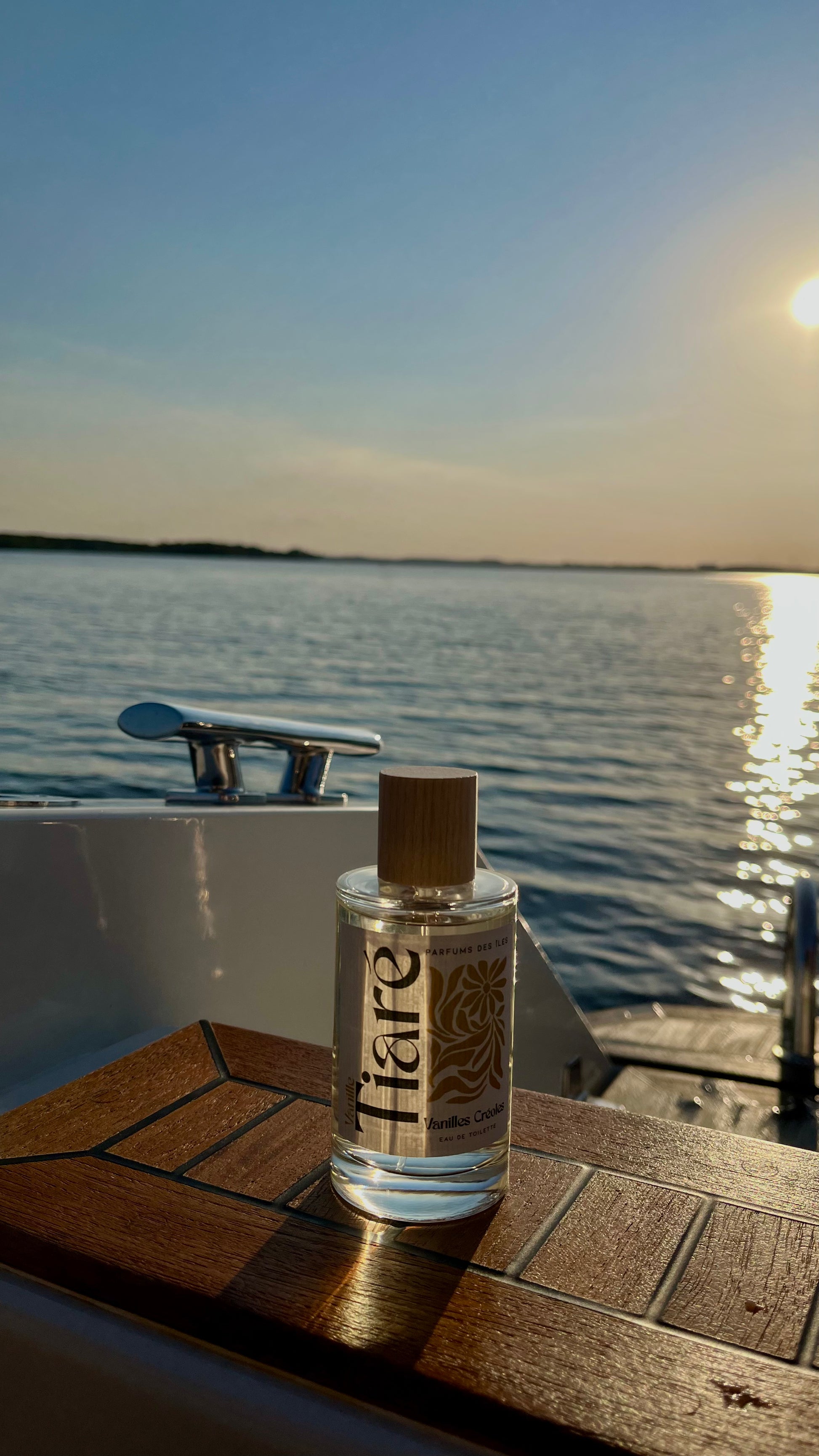 Eau de Toilette Tiare 100ml stehend auf einem Boot im Wasser. Im Hintergrund der See und Sonnenuntergang 