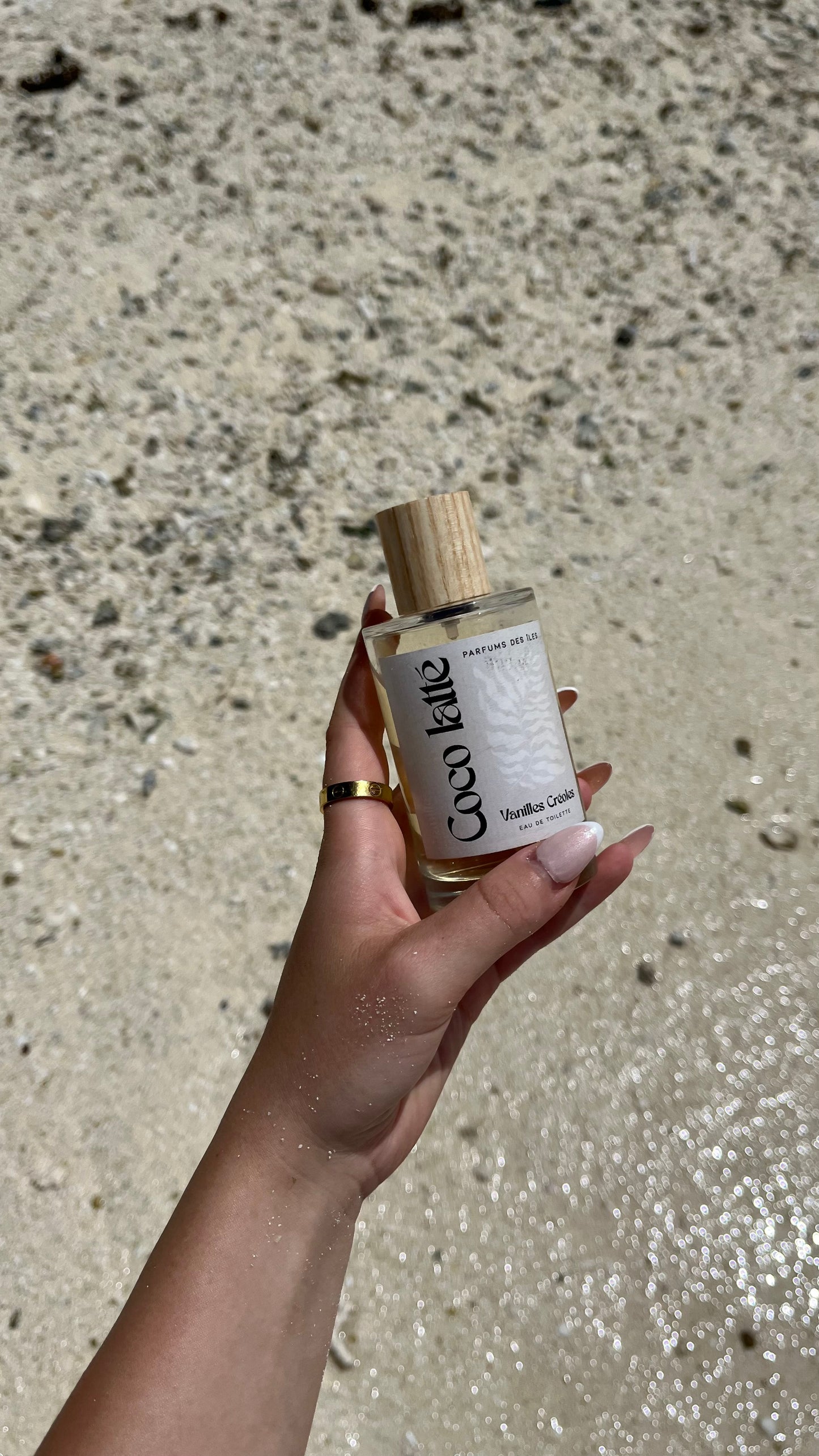 Eau de Toilette Coco Latte gehalten. Untergrund ist Sand